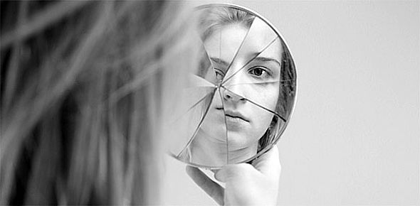 Mensch betrachtet sich in zerbrochenem Spiegel