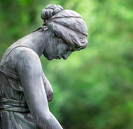 Statue einer jungen Frau mit traurig gesenktem Kopf