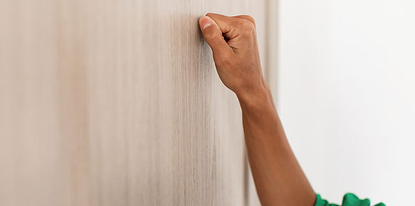 Frauenhand klopft an verschlossene Tür