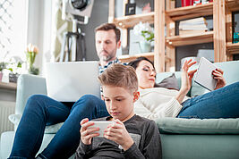 Vater, Mutter, Kind am Laptop, Tablet und Smartphone