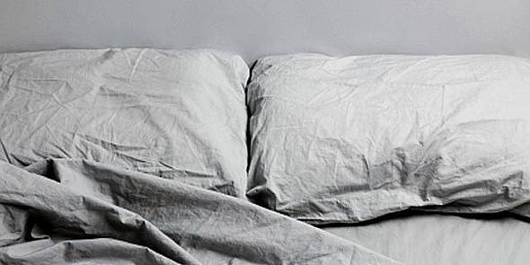 Leeres Bett mit zerknitterten Kissen