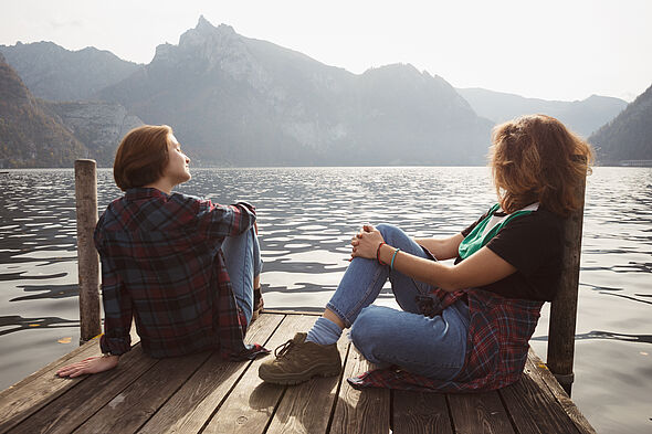 Zwei Frauen genießen an Bergsee die Sonne.