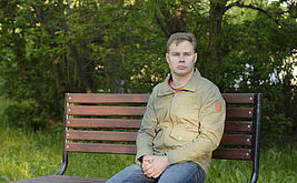 Mann sitzt alleine auf Parkbank