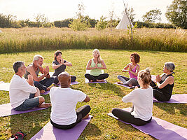 Erwachsene sitzen im Kreis und meditieren