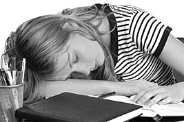 Junge Frau schläft mit Kopf auf Schreibtisch